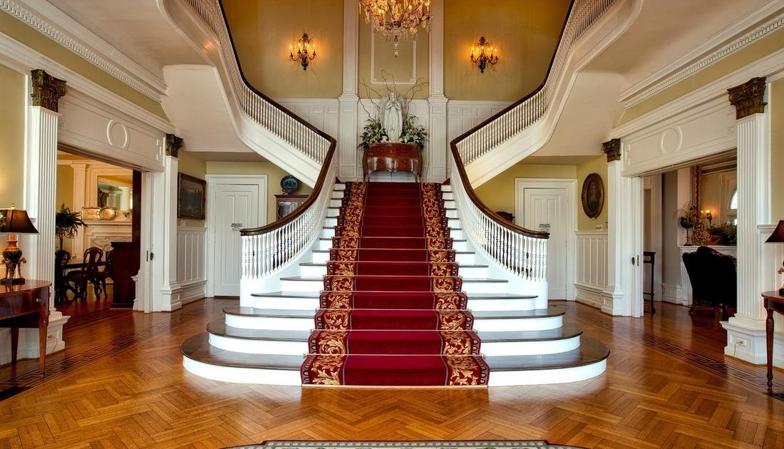Red and brown floral-patterned stair carpet adorning the interior of a bungalow, enhanced by the richness of the surrounding paintings and décor